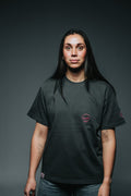 Person wearing a black t-shirt with a small logo on a dark background
