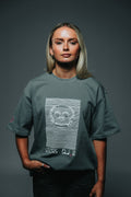 Person wearing a green t-shirt with a graphic design on a gray background