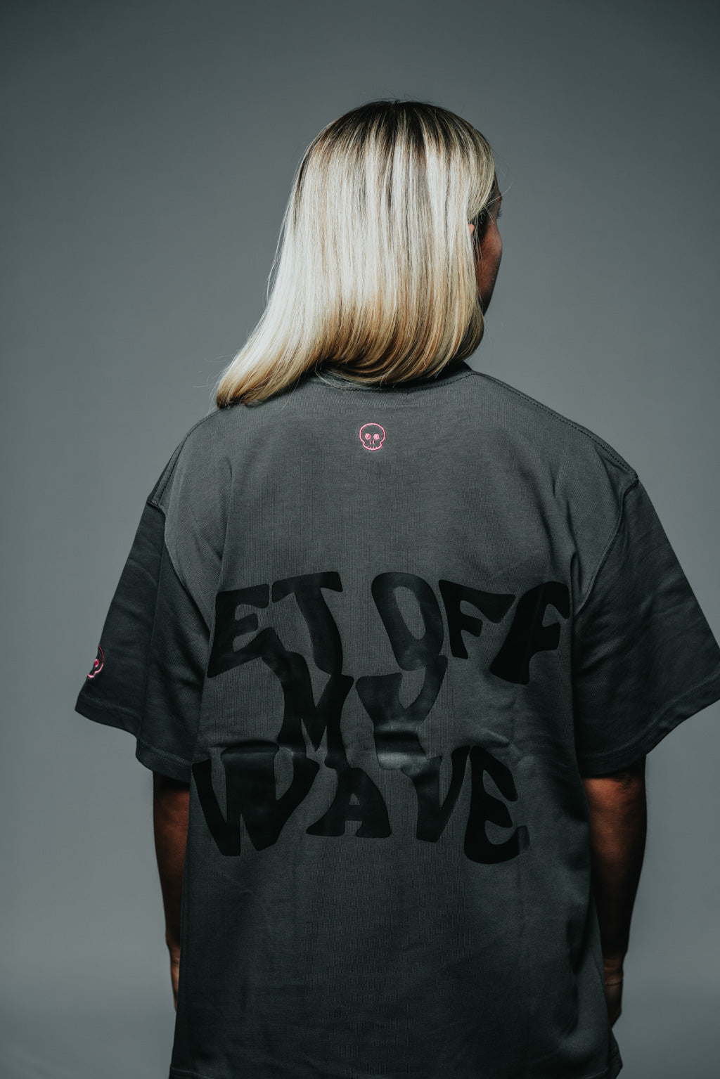 Person wearing a black t-shirt with text on the back against a gray background