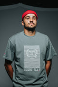 Man wearing a gray t-shirt with a skull design and red beanie against a gray background