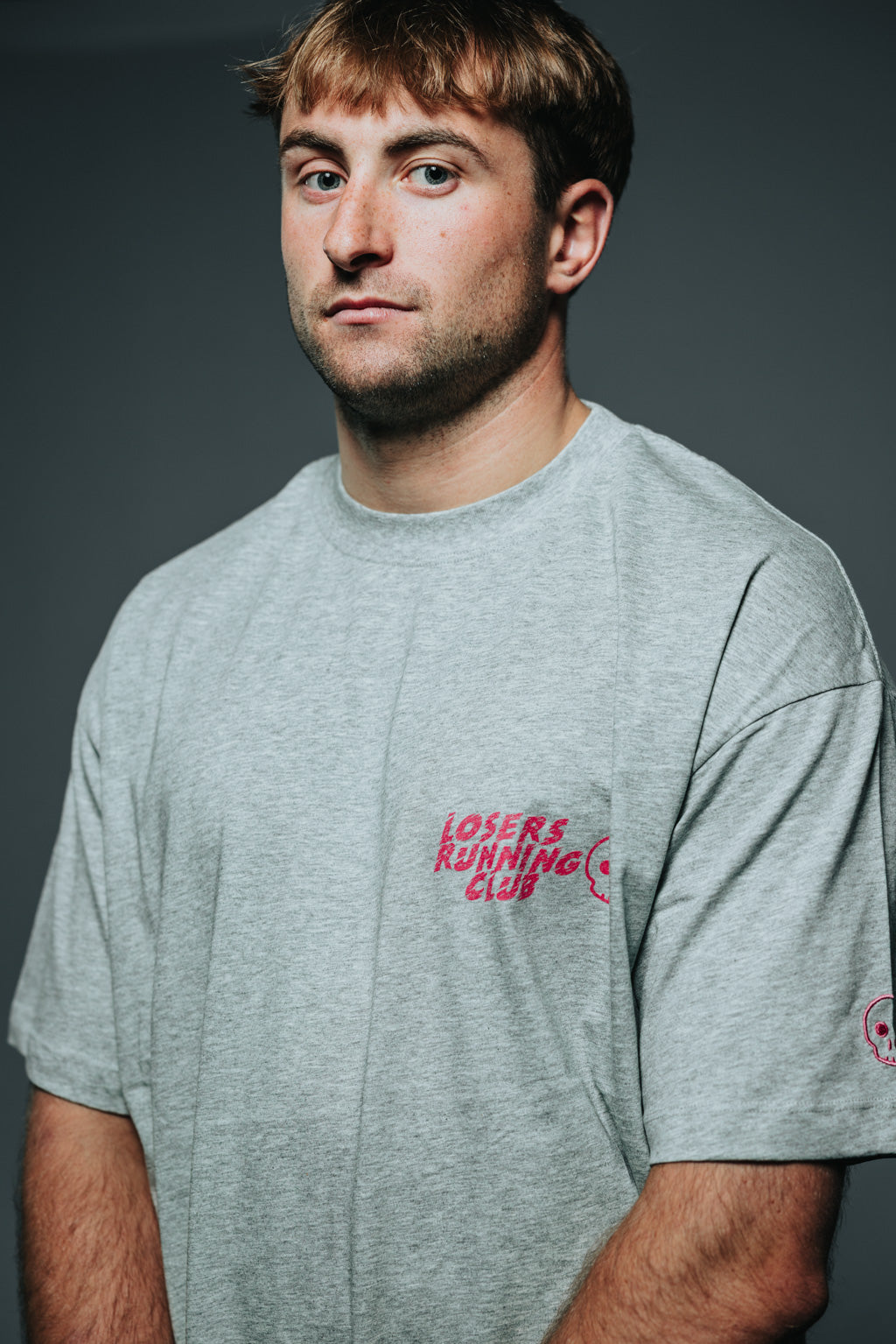 Man wearing a gray t-shirt with red text on a dark background