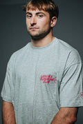 Man wearing a gray t-shirt with red text on a dark background