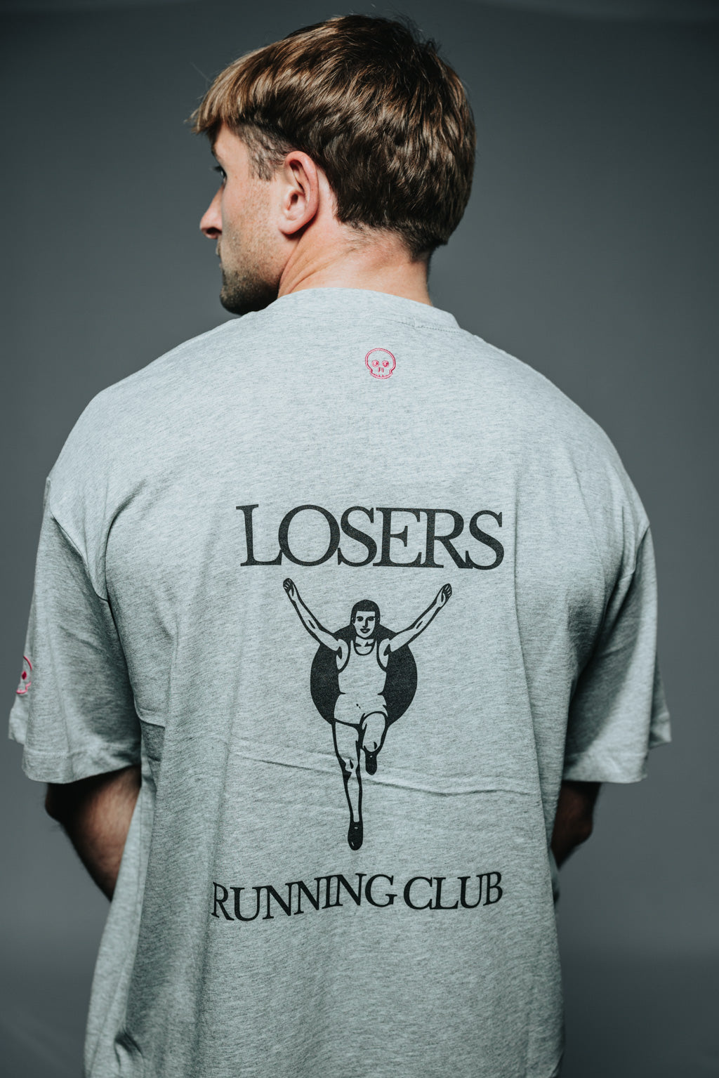 Man wearing a gray t-shirt with red text on a dark background