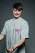Person wearing a gray t-shirt with a logo on a dark background