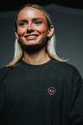 Person wearing a black sweatshirt with a pink skull design on a dark background