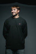 Man wearing a black sweatshirt with a small logo on a dark background