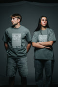 Two people wearing matching green t-shirts with a logo on a dark background