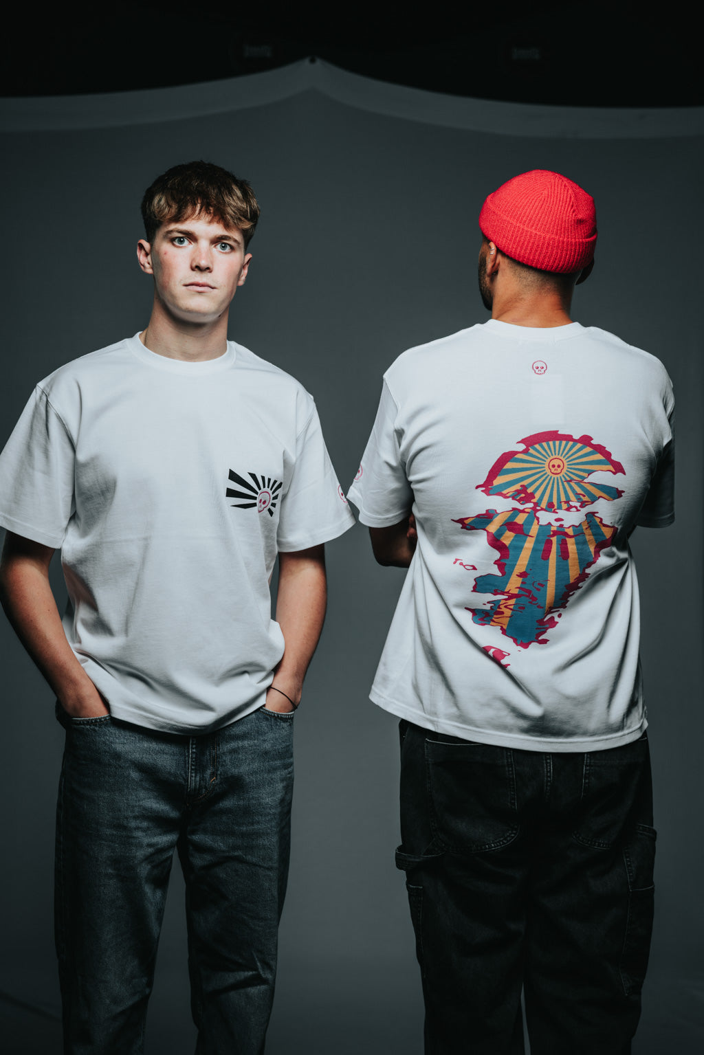 Two people wearing gray t-shirts with different designs on a dark background