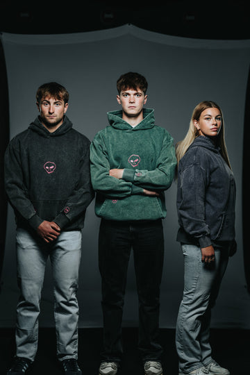 Three people wearing hoodies against a dark background