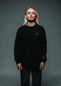 Person wearing a black sweatshirt with a small logo on a gray background