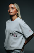Person wearing a white t-shirt with a black and red design on a dark background