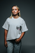 Person wearing a light gray t-shirt with a graphic design on a dark background