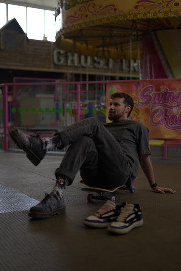 Person sitting on a skateboard with a colorful carousel in the background