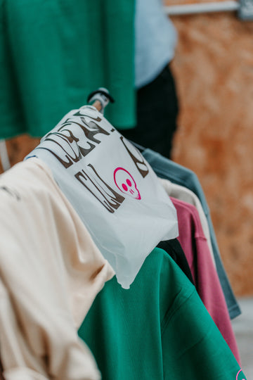 Clothing rack with various garments including a white shirt with text and graphics.