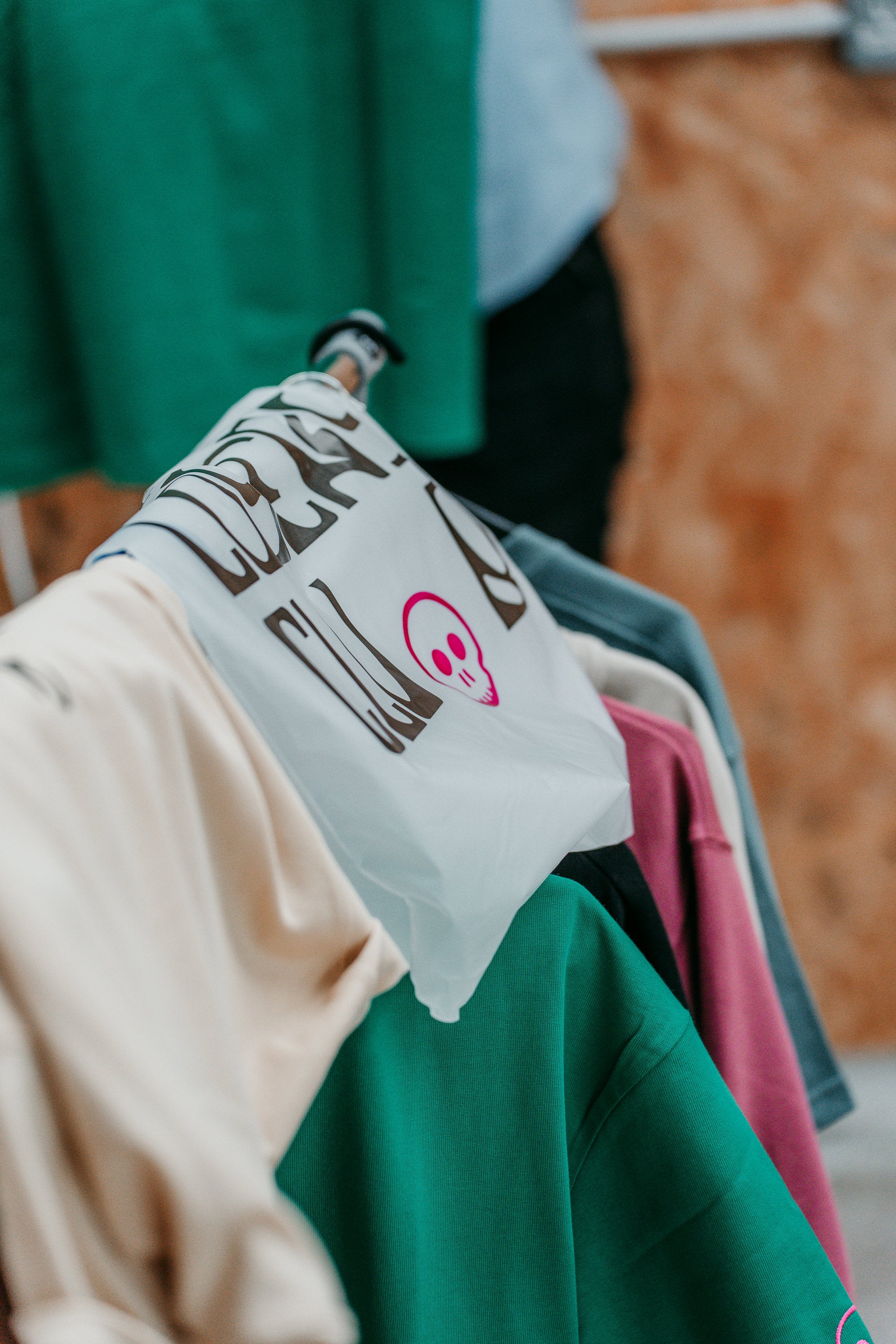 Clothing rack with various garments including a white shirt with text and graphics.slider_item_tbekki